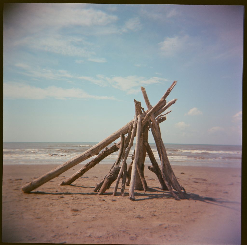 Sticks stacked in a pyramid shape on a beach