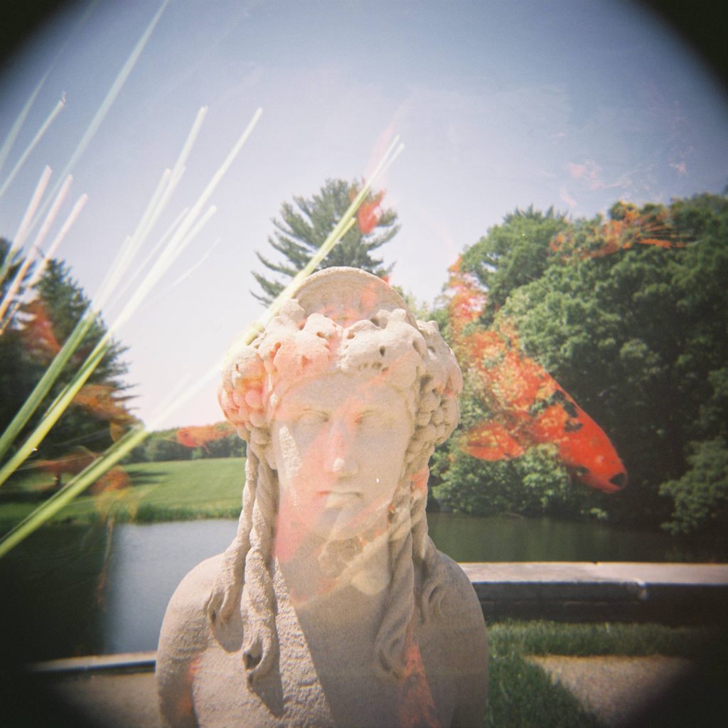 Double exposure of a sphynx statue and orange koi fish