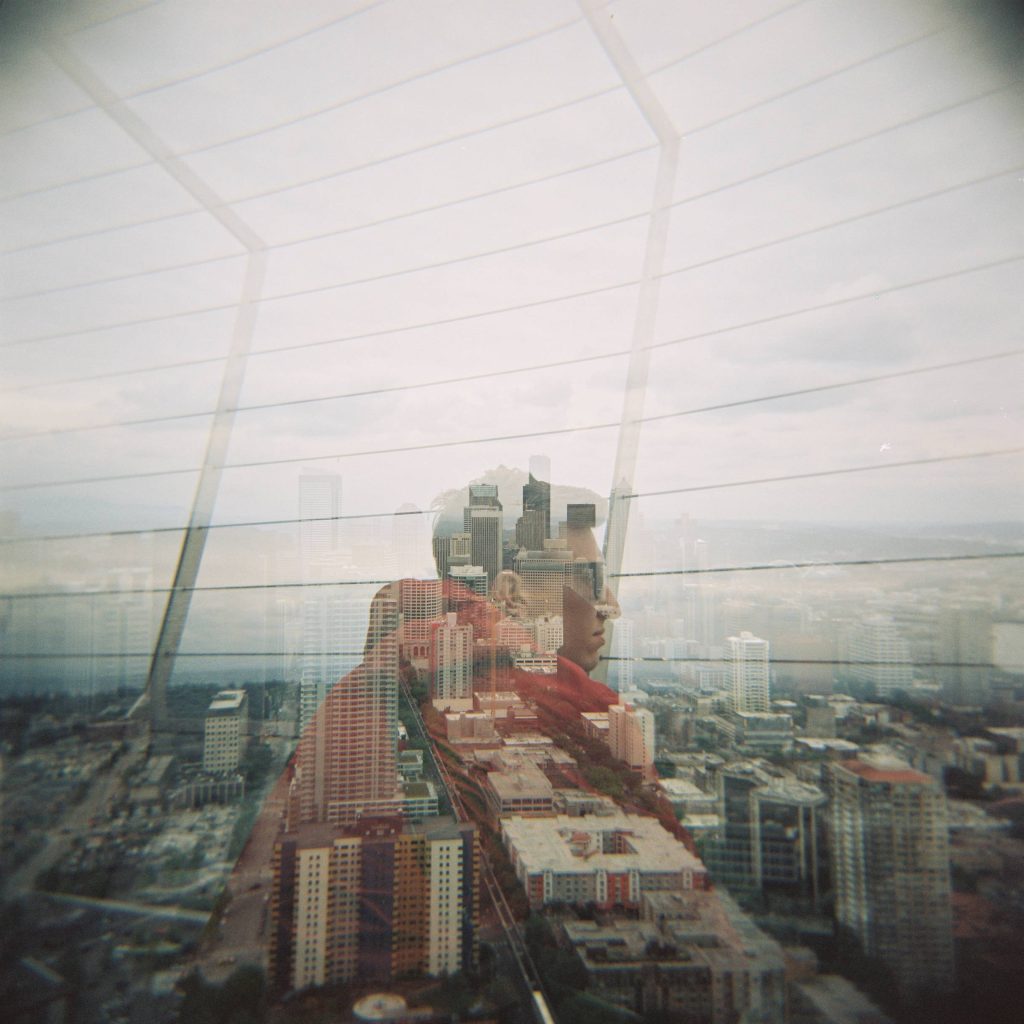 A double-exposure picture of a man looking over a city with the city skyline imposed over the picture